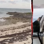 Brian Hooker assisted by boatyard employee after washing up in Marsh Harbour